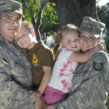 Master Sgt. Rodolfo Gamez and his wife, Tech. Sgt. Christina Gamez, hold their children, Tomas, 4, and Eva, 3, for a portrait outside of their home. The Gamezes are set to deploy to two different locations for year-long deployments later this year. (U.S. Air Force photo/Staff Sgt. Bennie J. Davis III)